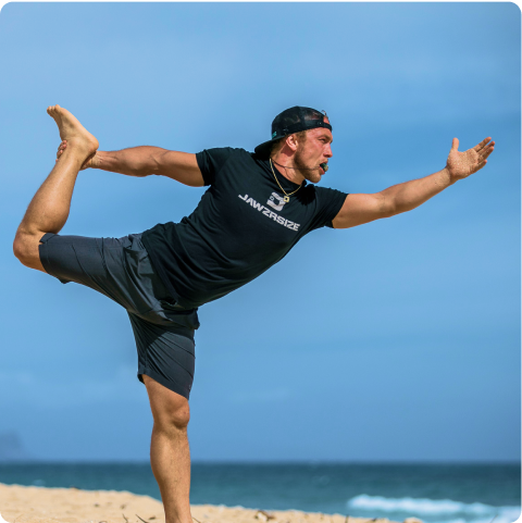 Man on beach in yoga pose wearing Jawzrsize shirt.